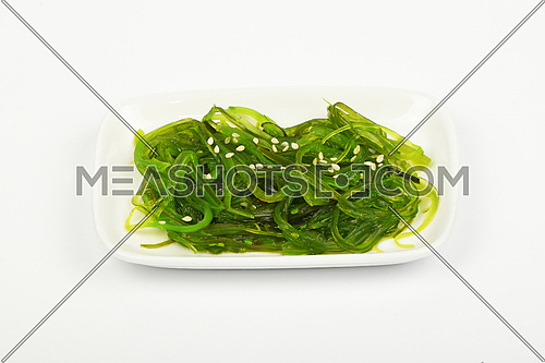 Portion of Asian traditional greed marinated seaweed salad appetizer on small white dish plate over white background, high angle view