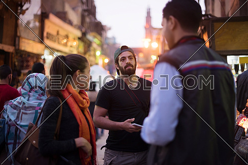 Young middle eastern tourists enjoy the city and talk to traders in the traditional street market