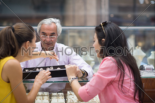 two young happy middle eastern women enjoy trying out jewelry in a luxury jewelry store