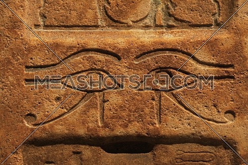 Close up background of antique stone wall with carved ancient Egyptian bas relief of wadjet, Eye of Ra or Horus, front view