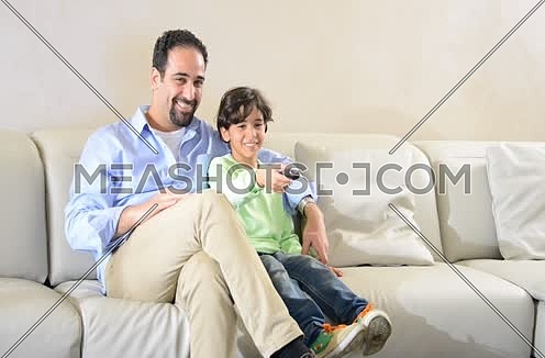 Mid shot for a father and son watching TV holding remot control