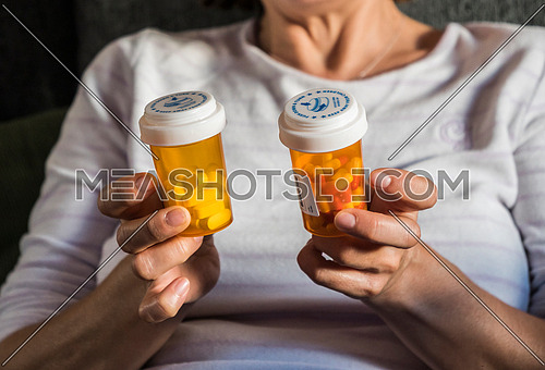 Woman examining medication treatment, several boats in the hand, conceptual image