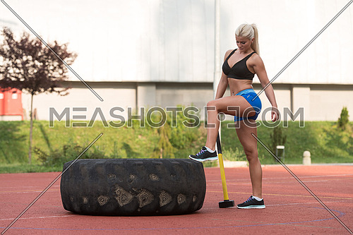 Portrait Of A Physically Fit Young Woman With Hammer And Tire Resting After Exercise