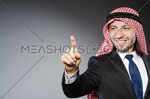 Arab businessman pressing virtual buttons against grey background