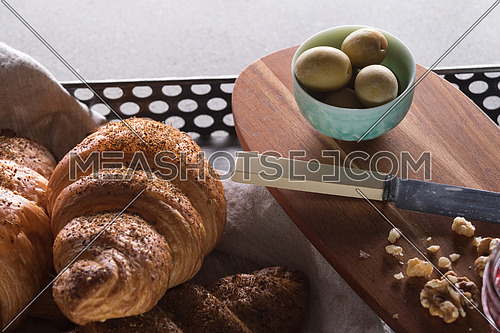 A tray of freshly baked croissant and a green bowl filled with green olives