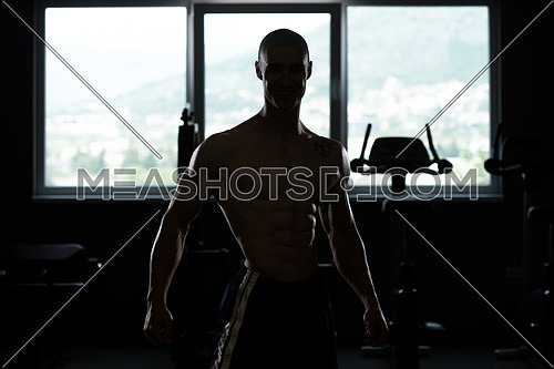 Silhouette Man Standing Strong In The Gym And Flexing Muscles
