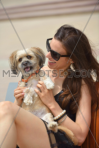 beautiful happy young  woman in black dress with cute small dog puppy have fun on street