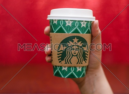 Starbucks takeaway paper cup, in special design for Christmas on a festive red background; December 2018 - Cairo, Egypt