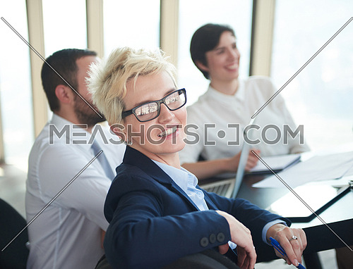 blonde with short hairstyle  and glasses,  business woman on meeting, people group in background at modern bright office indoors