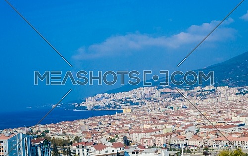 Landscape of a Turkish city by the ocean showing houses and small buildings and mosques