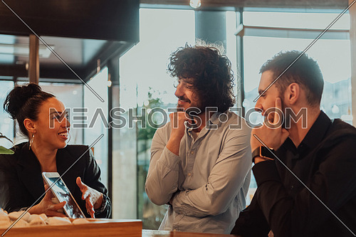 A group of friends hanging out in a cafe, and among them is a tablet. Happy young people sitting in a restaurant using tablets