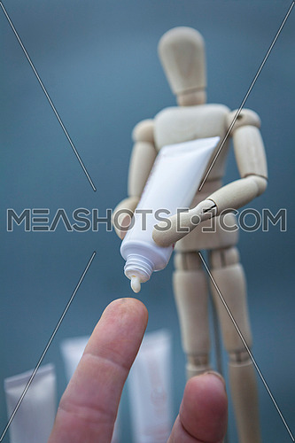 Articulated wooden doll with packing cremates dispenses cream on a finger