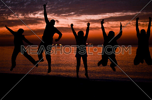 five friends jumping on the beach during sunset magical hour