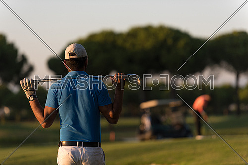 golfer  from back looking to ball and  hole in distance, handsome middle eastern golf player portrait from back with beautiful sunset in background