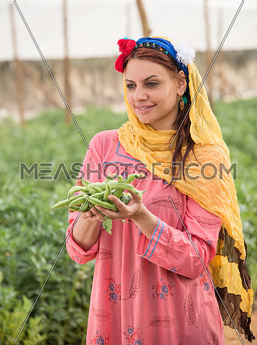 A female farmer holding raw broad beans in the palm of her hands