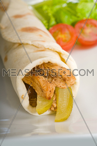 pita bread chicken roll with pickles cucumbers on a plate with pachino tomatoes and lettuce