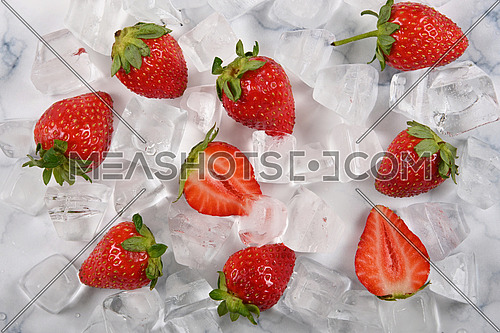Close up fresh red ripe strawberries and ice cubes on table, el;evated high angle view, directly above