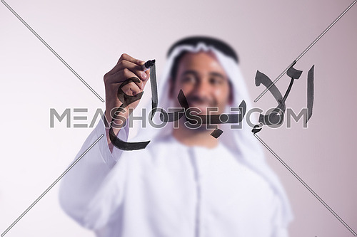 Arabian middle eastern man writing with a marker on virtual screen in arabic