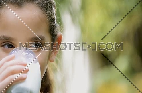 a cute little middle eastern girl drinking a glass of milk health concept