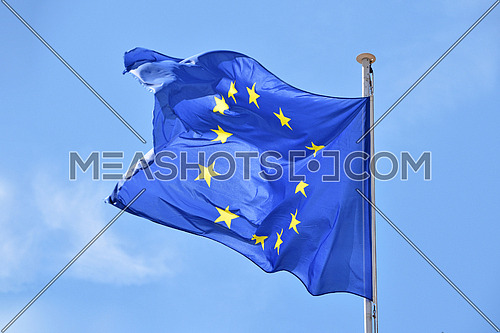 Close up flag of EU, European Union waving and blowing in the wind over blue sky, low angle view