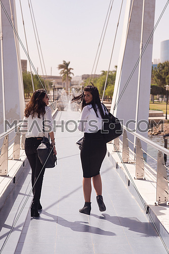 business woman group walking together across modern bridge at early mornig while drinking coffee