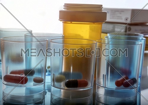 Several plastic glasses with daily medication in hospital, conceptual image