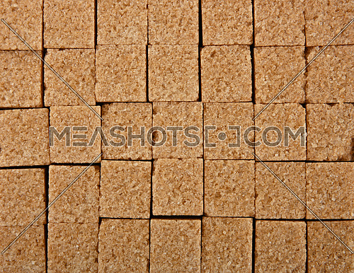 Close up background texture pattern of brown cane sugar cubes arranged