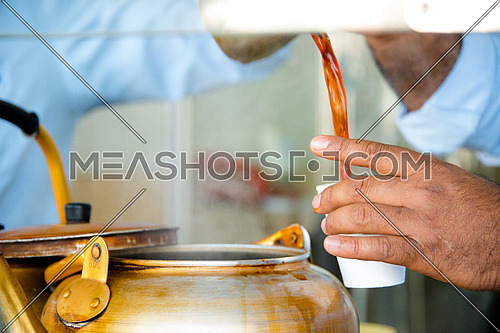 a man's hand pouring tea in foam cup