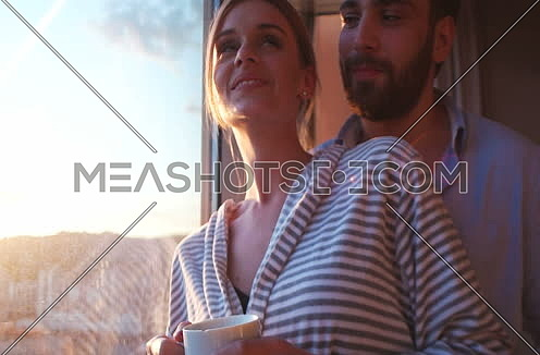 couple drinking coffee with sun flare coming from window. Sunset and couple