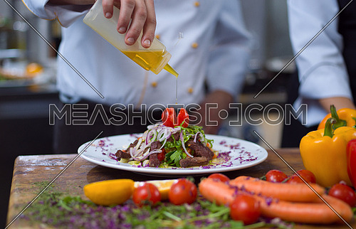 Chef finishing steak meat plate with Finally dish dressing and almost ready to serve at the table