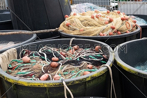 Fishing nets inside huge plastic bins on the waterfront after fishing day,quayside of the port of Varazze, Liguria Italy.
