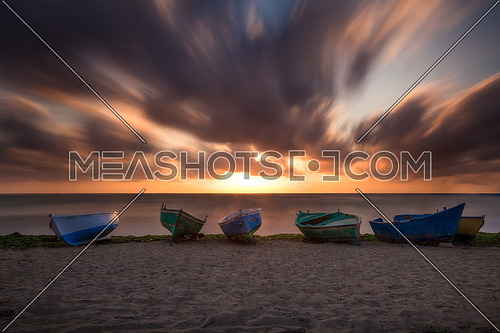 small rowing boats on a sandy beach at sunset