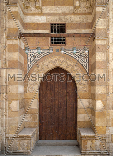 Wooden aged grunge door and stone bricks wall, one of the exterior doors of Aqsunqur Mosque (Blue Mosque) located in Bab El-Wazir District, Medieval Cairo, Egypt