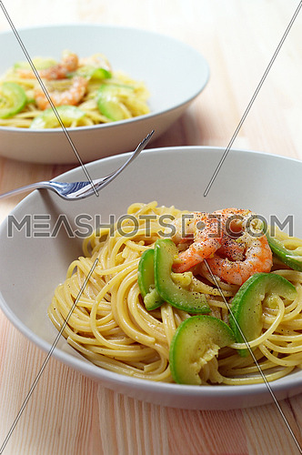 spaghetti pasta with fresh shrimps and zucchini sauce over wood table