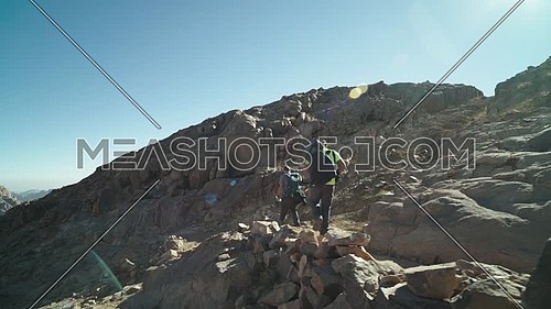 Follow shot for two male tourists exploring Sinai Mountain at day.