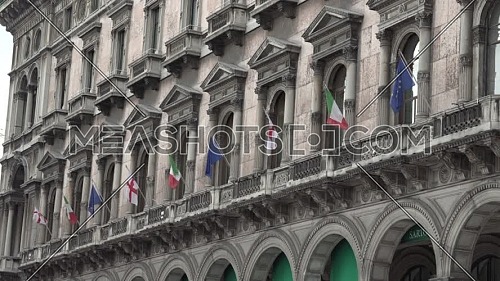 Many italian ,european and Milan  flags in the wind on the ancient palace in the center of Milan.Italy.