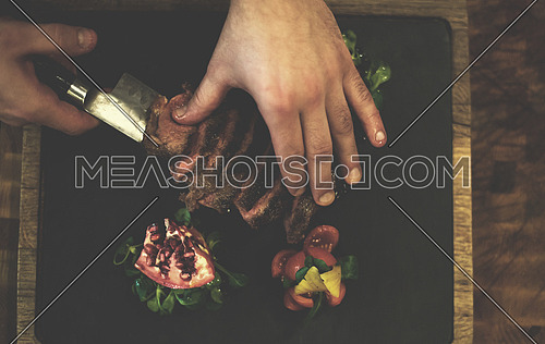 top view of Chef hands in hotel or restaurant kitchen serving beef steak with vegetable decoration