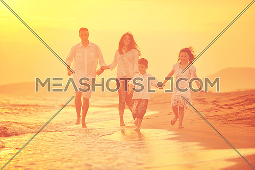 happy young family have fun on beach run and jump  at sunset