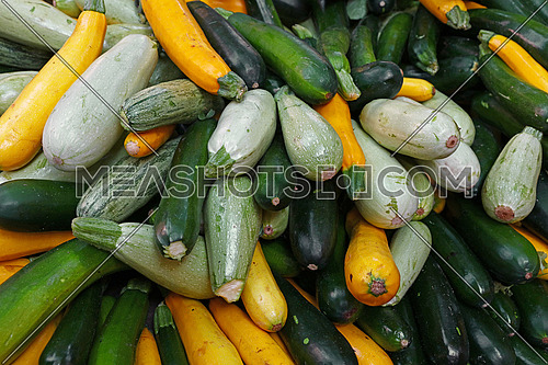 Close up fresh new green and yellow zucchini on retail display of farmers market, high angle view