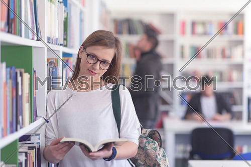 portrait of smart looking famale student girl  in collage school library reading book