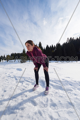 yougn woman resting taking breath while jogging outdoor on snow in forest, healthy winter lifestyle and recreation