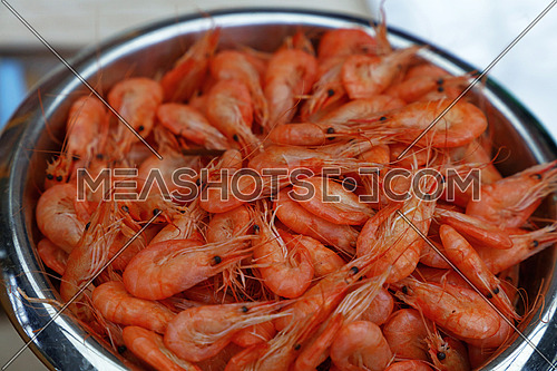 Metal bucket of fresh boiled or steamed small pink shrimps on retail market display, close up, high angle view