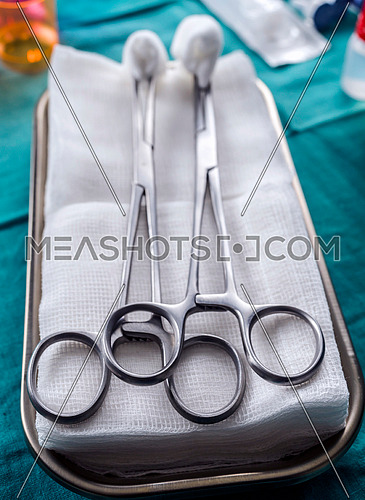 Scissors surgical with torundas on a tray metal in an operating theater, conceptual image
