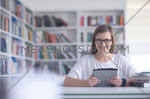 female student study in school library, using tablet  and searching for informations on internet