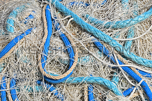 Close up background of heap coils of sea fishing net with colorful vivid floats and cable ropes at harbor