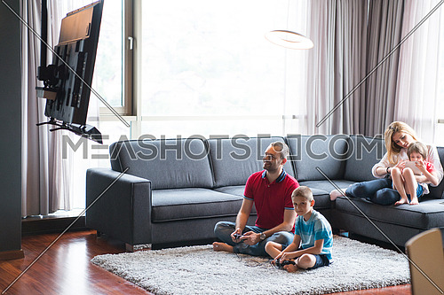 Happy family. Father, mother and children playing a video game Father and son playing video games together on the floor