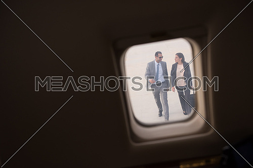 Young middle eastern successful businessman and businesswoman walking towards private jet