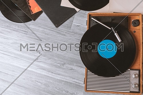 Vintage Gramophone with a vinyl record on gray wooden table, top view and copy space.