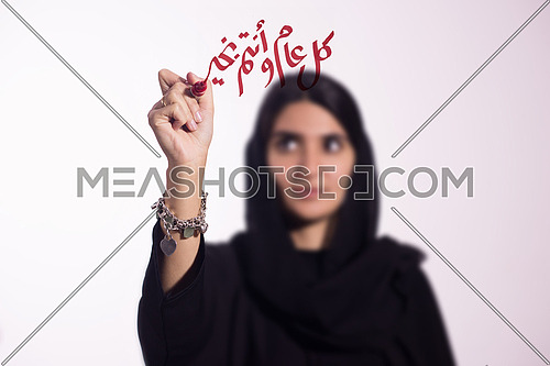 Arabian middle eastern business woman writing with a marker on virtual screen in arabic كل عام و انتم بخير suggesting season greeting "happy new year" "Happy Birthday"
isolated on white background