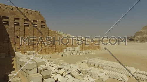 Pan Left form Saqqara Pyramid till an ancient ladder of small temple ruins at day.